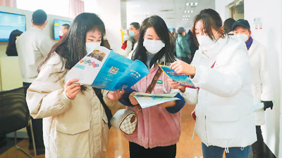 12月16日，新疆维吾尔自治区公共就业服务中心举办2022年“暖冬送岗·助企复产”综合现场招聘会，吸引众多求职者前来求职。图为求职者在乌鲁木齐招聘会现场了解情况。张秀科摄（人民视觉）